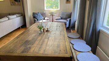 Un comedor con mesa de madera, asientos acolchados y ventana con vista a follaje.