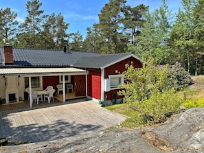 Eine rote Holzhütte mit einer überdachten Veranda, Sitzgelegenheiten im Freien und einem Kamin.