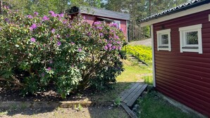 Une cabane rouge avec un petit porche et une terrasse en bois.