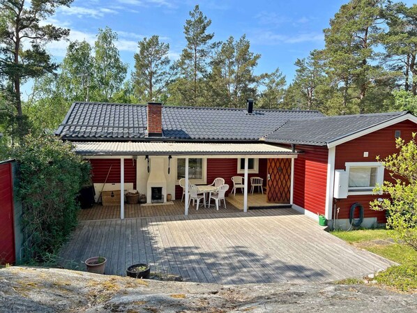 Punainen puutalo, jossa on katettu terassi, takka ja pieni parveke.
