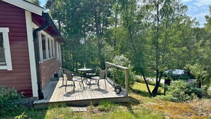 Une terrasse en bois, avec des meubles d’extérieur, une petite table et une rambarde.