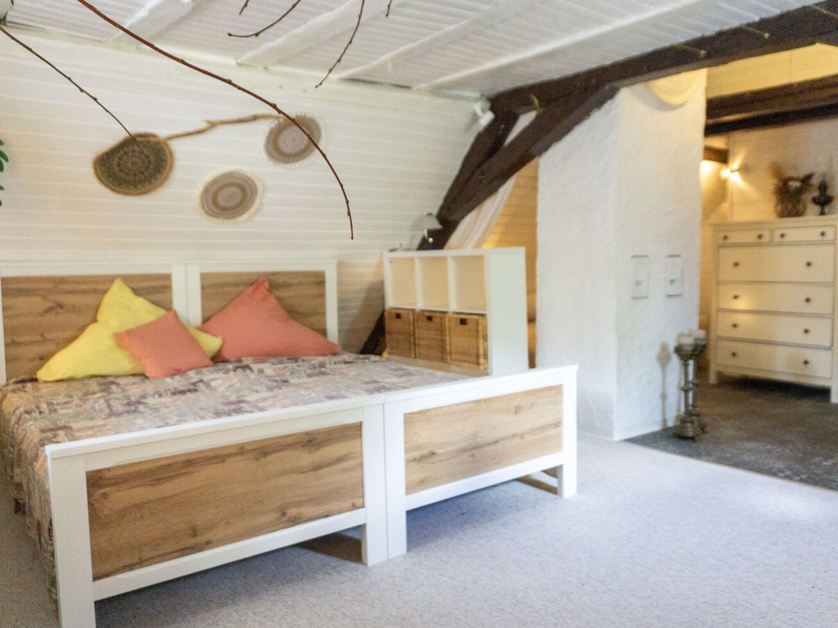 A bedroom with a wooden bed, a dresser, and a ceiling with exposed beams.