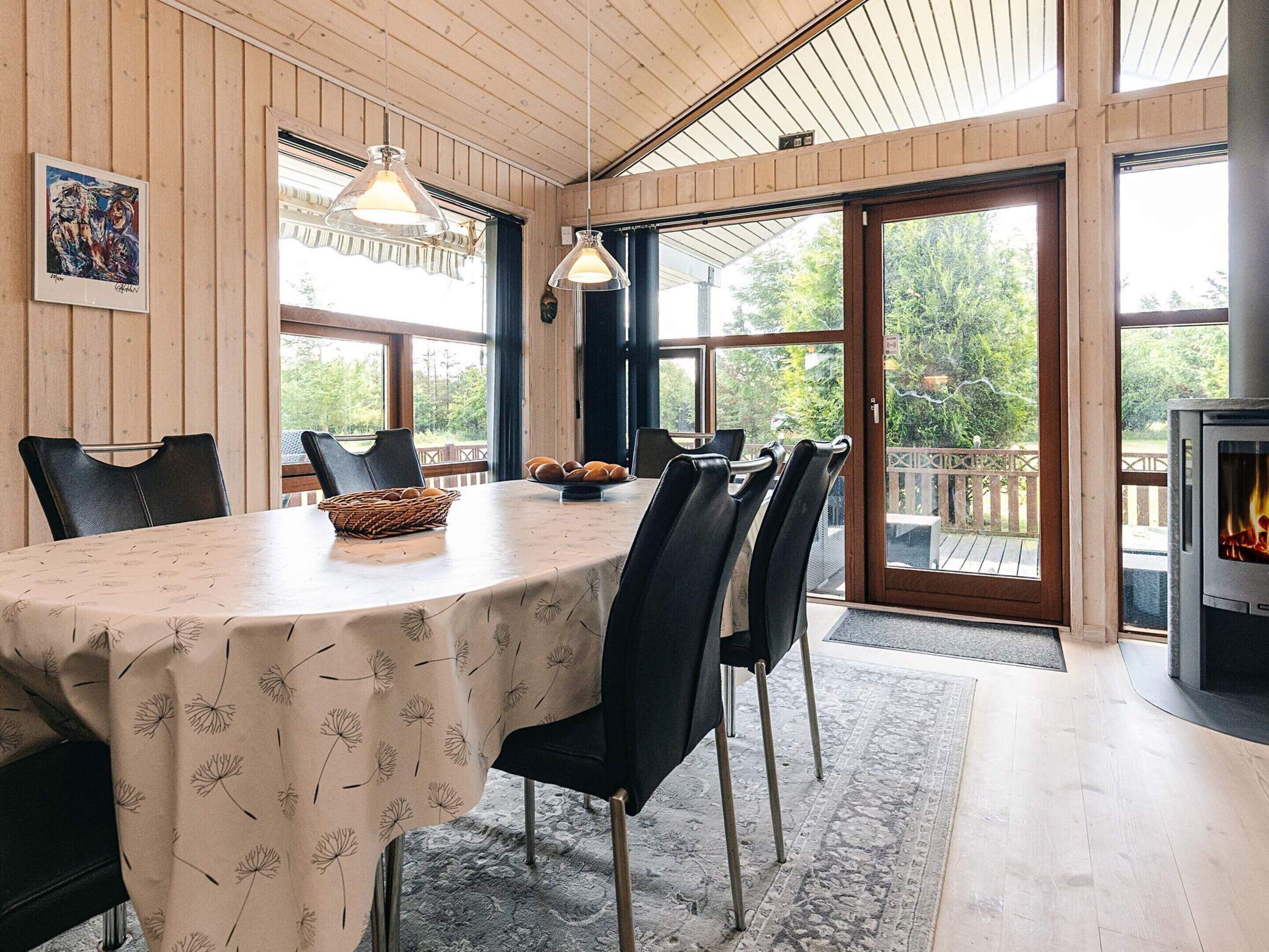 Un comedor con una mesa dispuesta para cuatro personas, rodeada de sillas, y una cesta de pan sobre la mesa.
