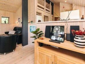 Un salon moderne avec un plancher en bois, un canapé en cuir noir, une table basse en bois et une grande enceinte noire.