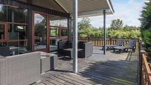 A covered outdoor deck with wicker furniture and a wooden floor. - 4 Star Holiday Home in Oster Assels (Øster Assels)