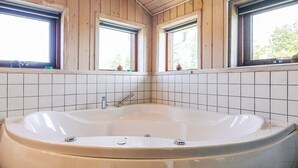 A bathroom with a large bathtub, wooden walls, and tiled flooring. - 4 Star Holiday Home in Oster Assels (Øster Assels)