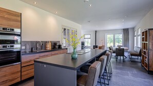 Una cocina moderna con una isla central, taburetes de bar y un comedor con mesa y sillas.