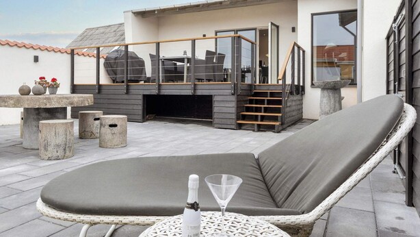Une terrasse sur le toit, dotée d’un espace salon avec des coussins, d’une petite table et d’un barbecue.
