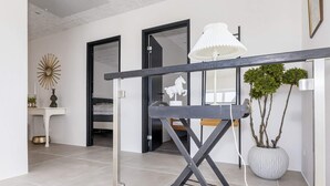Une chambre moderne au design minimaliste, avec une table en métal gris, une lampe blanche et une plante en pot.