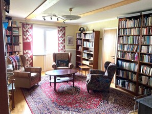 A cozy living room with a fireplace, a large bookshelf, a patterned rug, and a comfortable seating area. - 4 Person Holiday Home in Burtrask (Burträsk)