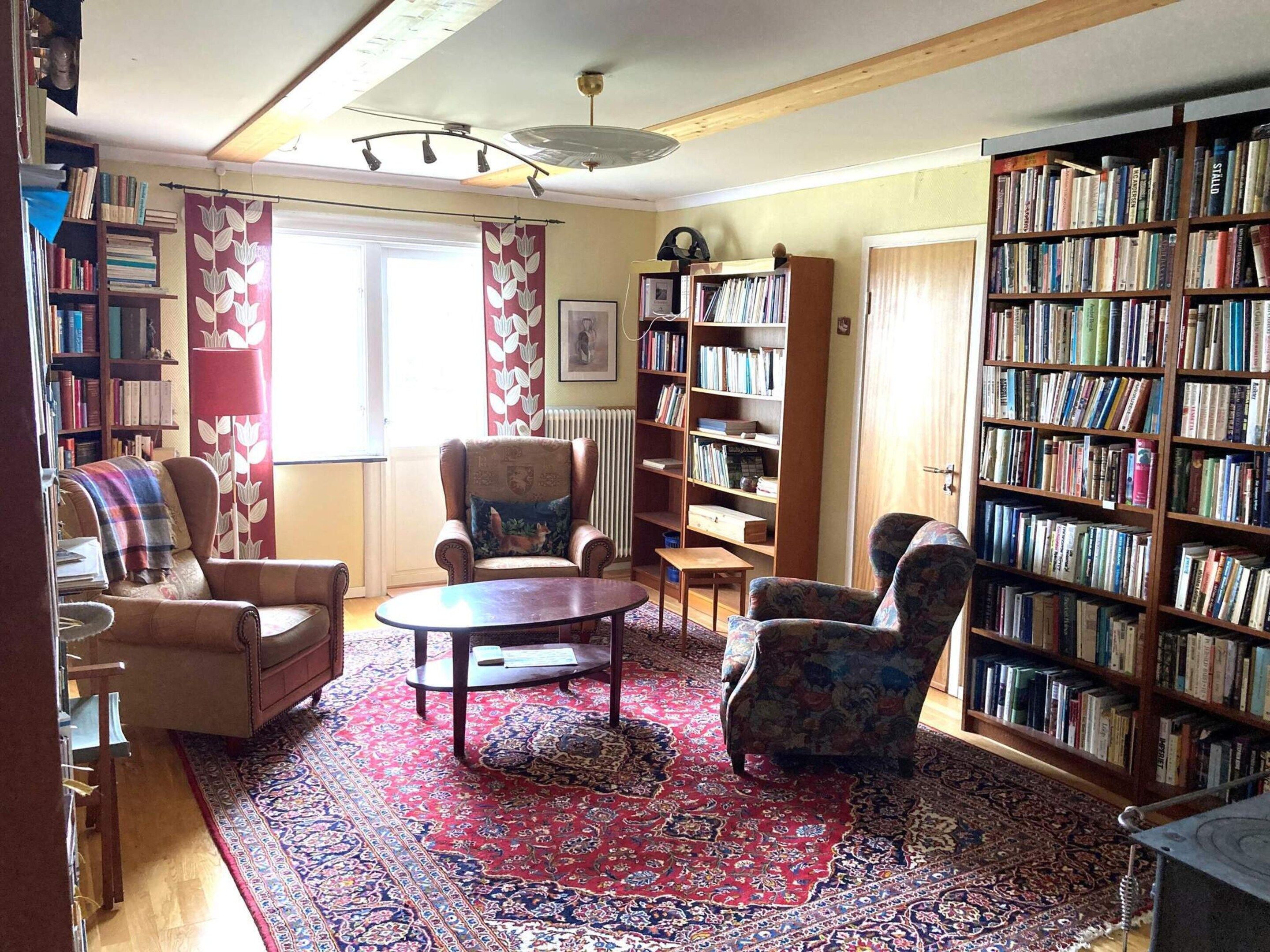 Una sala de estar acogedora con chimenea, una estantería y un ventanal grande.