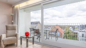 A modern balcony with a view of residential buildings, a cushioned chair, a small table, and a decorative apple. - Apartment in Middelkerke Near Sandy Beach (Middelkerke)