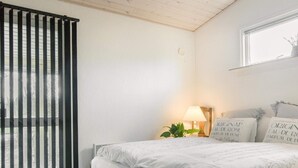 Une chambre à coucher avec un lit, une fenêtre, une lampe et une plante.