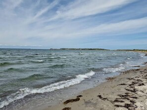 A beach with waves, a sandy shore, and a distant landmass. - 5 Person Holiday Home in Follenslev (Follenslev)