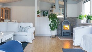 Un salon chaleureux avec une cheminée, des meubles blancs et un plafond en bois.