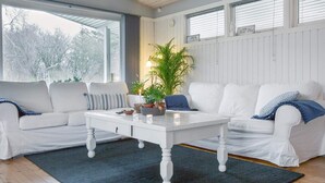 Un salon avec deux canapés blancs, une table basse blanche et une grande plante en pot.