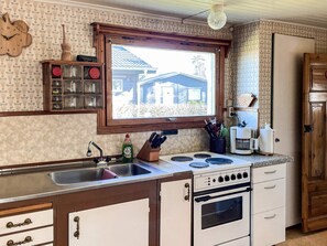 A vintage kitchen with a window, a sink, a stove, and a refrigerator.