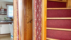 A narrow wooden hallway with a red patterned door and a red carpeted wall. - 5 Person Holiday Home in Solvesborg (S ölvesborg)
