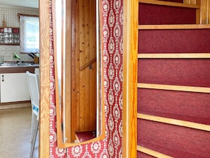 A narrow wooden hallway with a red patterned door and a red carpeted wall. - 5 Person Holiday Home in Solvesborg (Sölvesborg)