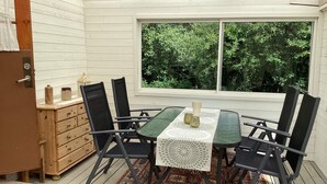 A dining area with a table and chairs, a window with a view of greenery, and a wooden chest of drawers. - 5 Person Holiday Home in Solvesborg (Sölvesborg)