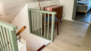 A staircase with a wooden handrail and a metal railing, leading to a room with a bed and a desk. - 5 Person Holiday Home in Solvesborg (Sölvesborg)