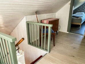 A staircase with a wooden handrail and a metal railing, leading to a room with a bed and a desk. - 5 Person Holiday Home in Solvesborg (Sölvesborg)