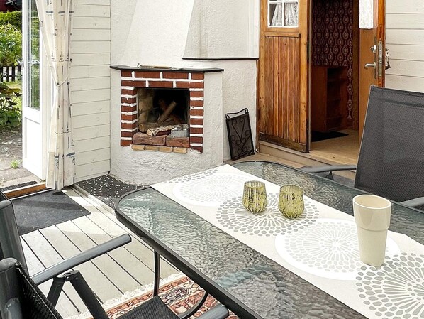 An outdoor patio with a glass table, two candle holders, and a white cup. - 5 Person Holiday Home in Solvesborg (Sölvesborg)