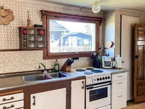 A kitchen with a window, a sink, a stove, and cabinets.