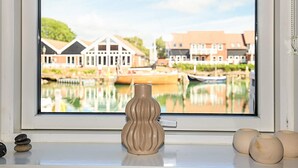 A window with a view of a calm water body, buildings, and a decorative vase on the window sill. - 5 Person Holiday Park Home in Borre (Borre)