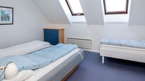 A bedroom with a sloped ceiling, two windows, a bed, a dresser, and a radiator. - 5 Person Holiday Park Home in Borre (Borre)
