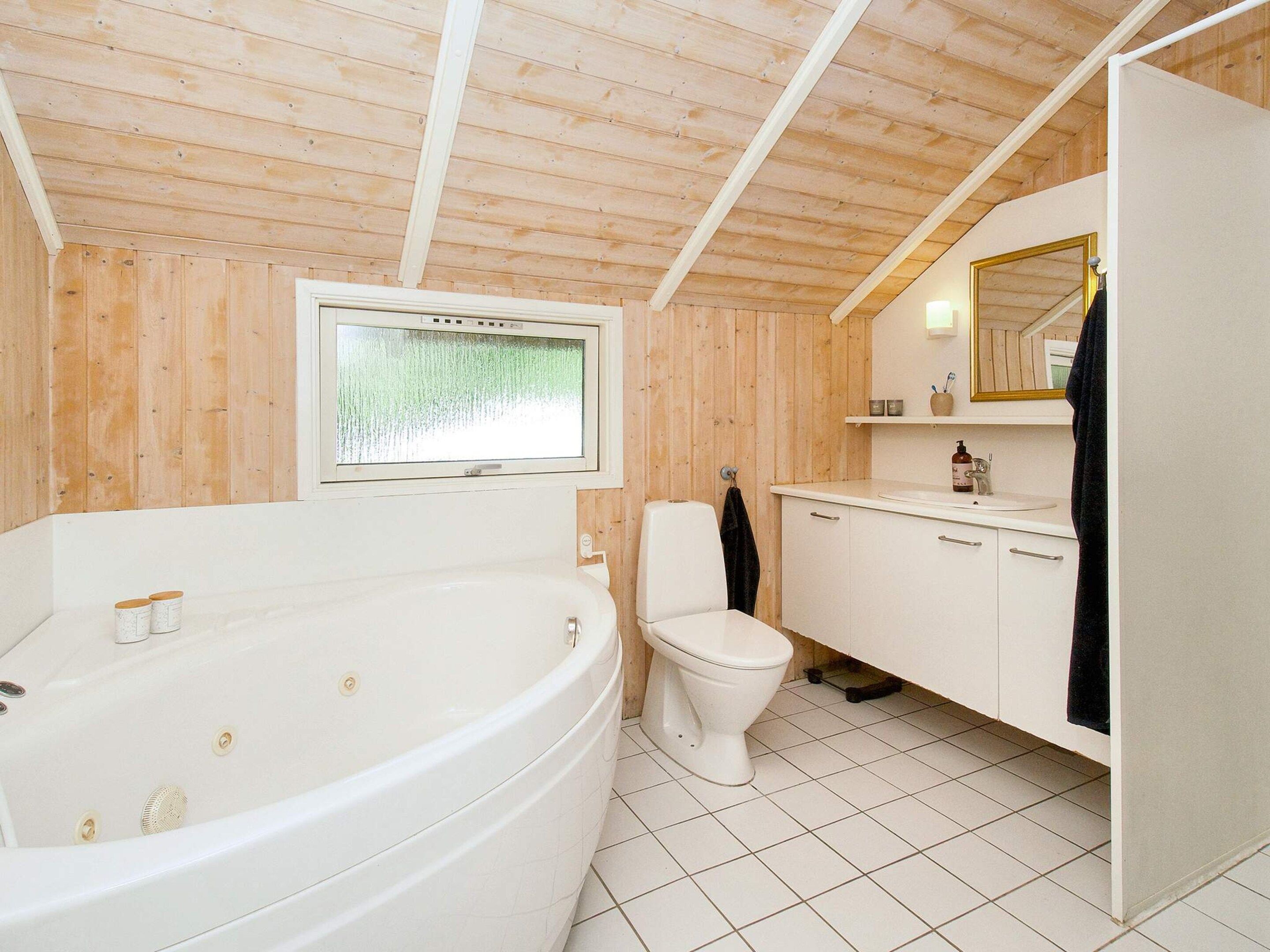 A modern bathroom with a freestanding bathtub, a toilet, and a sink with a mirror above.
