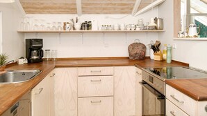 A kitchen with wooden cabinets, a coffee maker, and various kitchen utensils on the countertop. - 6 Person Holiday Home in Graested (Graested)