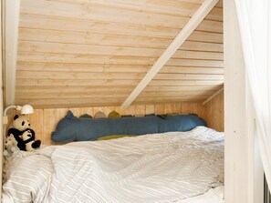 A bedroom with a wooden ceiling, a bed with striped bedding, and a panda plush toy. - 6 Person Holiday Home in Graested (Graested)