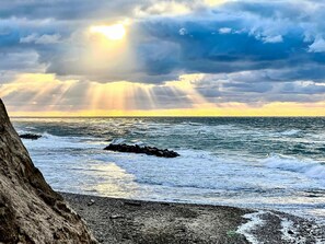 A rocky shoreline with waves, a tree, and a sunset. - 6 Person Holiday Home in Graested (Graested)
