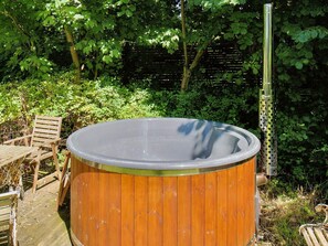 A wooden hot tub with a metal frame, surrounded by greenery and a wooden deck with chairs. - 6 Person Holiday Home in Graested (Graested)