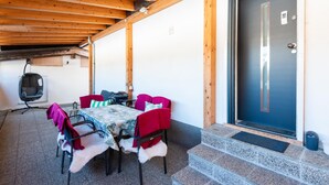 An outdoor covered patio with a table and chairs, a hanging chair, and a door with a keypad lock. - Chalet in Zillertal Near Ski Slopes (Ramsau im Zillertal)