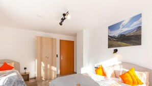A modern bedroom with a large bed, a smaller bed, a wardrobe, and a painting on the wall. - Chalet in Zillertal Near Ski Slopes (Ramsau im Zillertal)