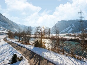 A snow-covered landscape with a river, mountains, and a power line tower. - Chalet in Zillertal Near Ski Slopes (Ramsau im Zillertal)