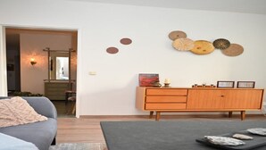 A modern living room with a grey sofa, a dark coffee table, and a wooden cabinet with decorative plates on the wall. - Vintage Style Apartment With Balcony/terrace (Bremen)