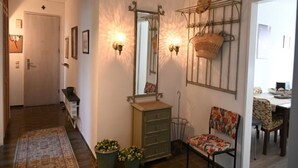 A hallway with a wooden door, a bench, a dresser, a chair, and a dining area with a table and chairs. - Vintage Style Apartment With Balcony/terrace (Bremen)