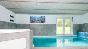 An indoor swimming pool with a view of the outdoors, a painting on the wall, and a wooden floor. - 4 Star Holiday Home in Nordborg (Nordborg)