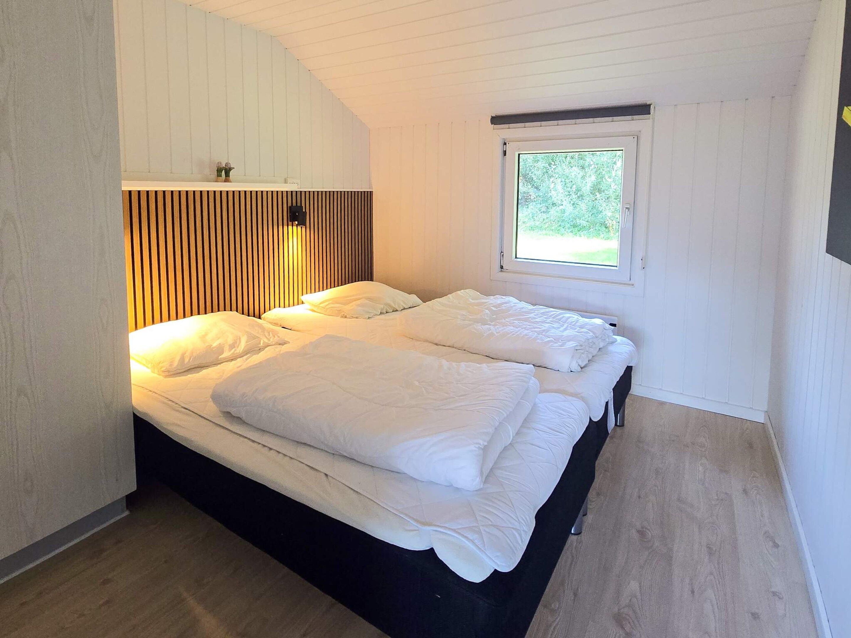 A room with a bed, a window, and a wall-mounted light fixture.