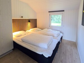 A room with a bed, a window, and a wall-mounted light fixture.