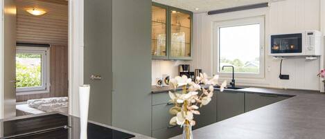 A modern kitchen with a built-in oven, a microwave, and a window providing natural light.