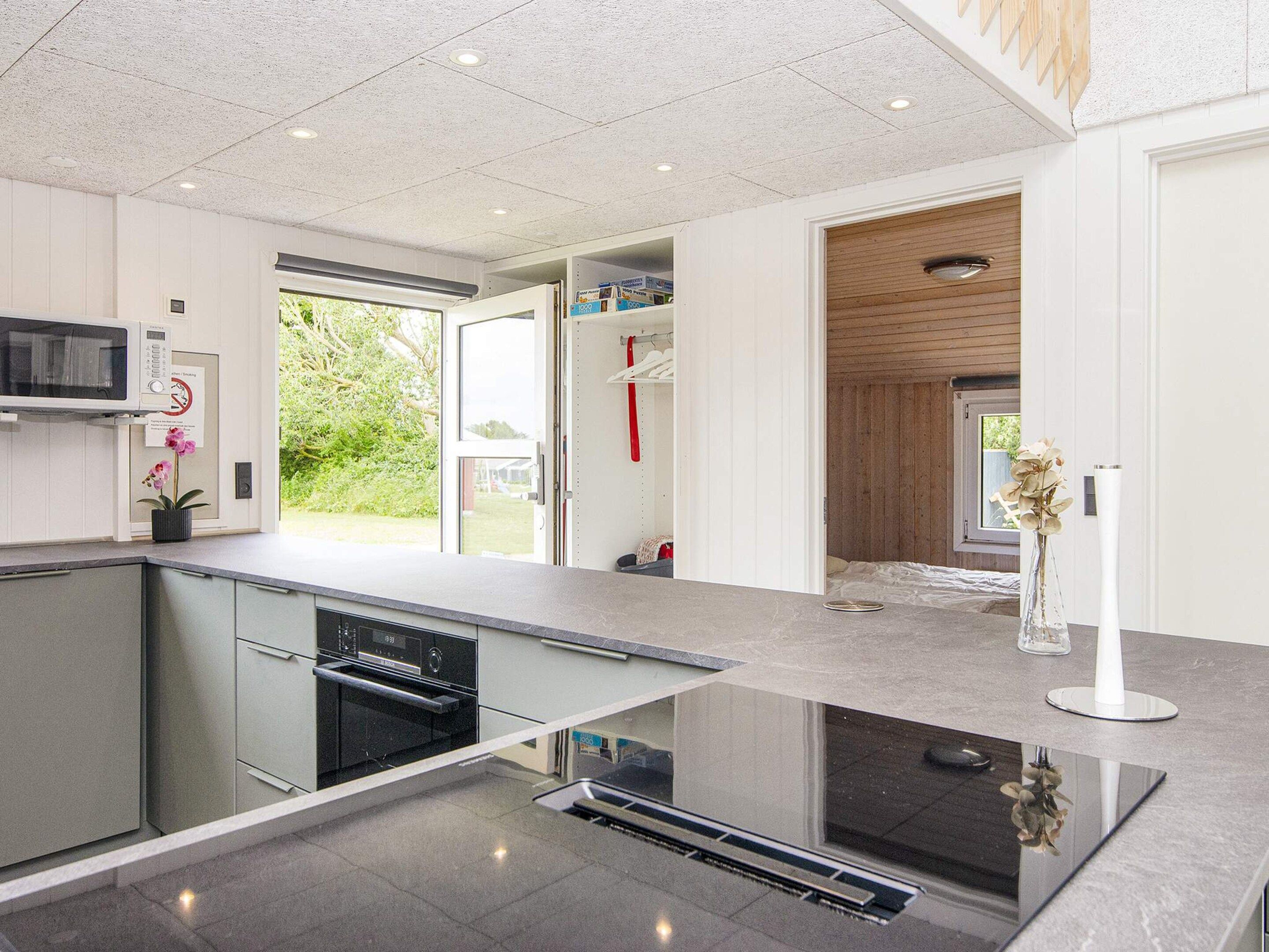 A modern kitchen with a built-in microwave, a sink, and a window overlooking a garden.
