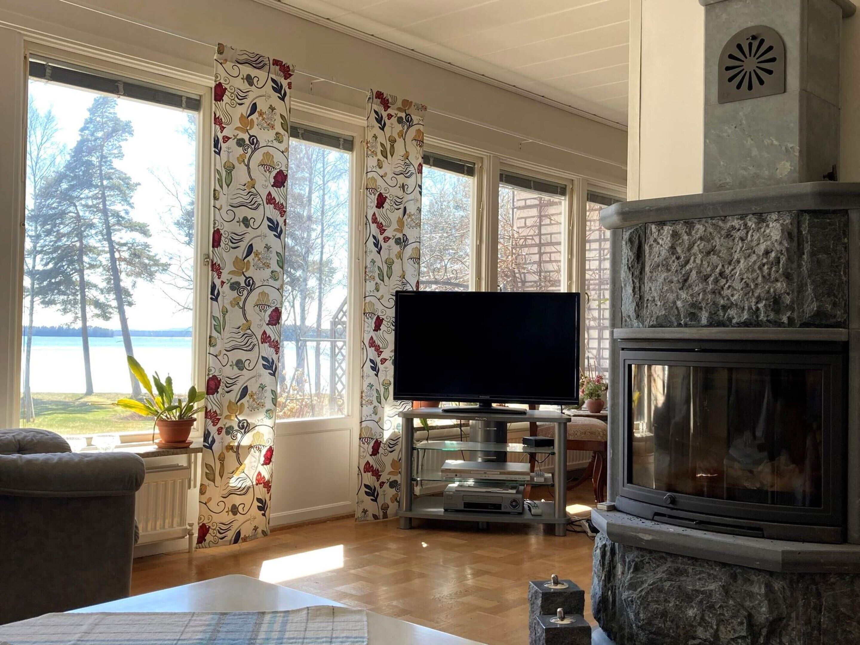 Una sala de estar con chimenea, televisor y vista a un lago.