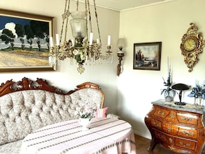A bedroom with a large bed, a chandelier, a dresser, and two framed paintings. - 4 Star Holiday Home in Karlsborg (Karlsborg)