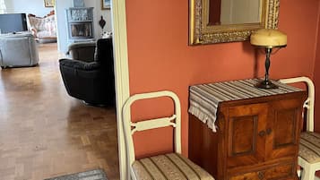 Ein Zimmer mit einem hölzernen Schminktisch, zwei Polsterstühlen, einem Fernseher und einem Spiegel an der Wand.