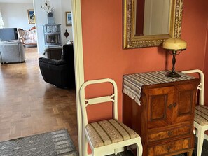 A room with a wooden dresser, two upholstered chairs, a television, and a mirror on the wall. - 4 Star Holiday Home in Karlsborg (Karlsborg)