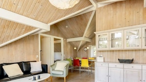 A cozy, wooden interior with a dining area, a sofa, and a kitchen.
